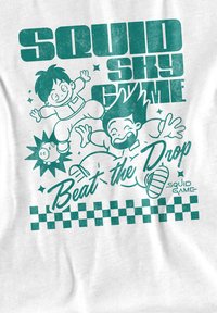 Weißes T-Shirt mit türkisfarbigem grafischen Design und Cartoonfiguren. Text lautet "Squid Sky Game" und "Beat the Drop." Schachbrettmuster am unteren Rand.