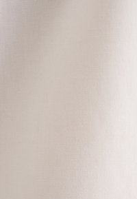 Gros plan sur la texture d'un tissu beige lisse avec un motif tissé fin et une subtile ombre lumineuse.