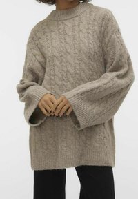Light brown knit sweater featuring a cable design, high neck, oversized sleeves, and ribbed cuffs. Soft texture with a relaxed fit.