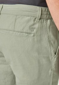 Hellegrüne Hose aus strukturiertem Stoff. Mit elastischem Bund, Seitentaschen und einem gestickten Logo auf der Gesäßtasche.