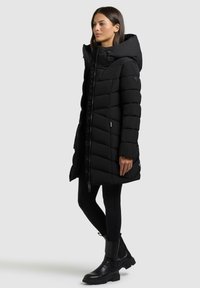 Svarte boblejakker med høy krage, skrå quilting og glidelåslukking. Kombinert med svarte bukser og kraftige svarte ankelstøvler.