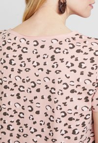 Camiseta rosa con un diseño de estampado de leopardo en negro y blanco. Tejido suave con un corte relajado y escote amplio.