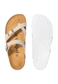 Beige sandaler med justerbare krydsremme, en blød ruskindsindlæg og en tekstureret hvid gummisål med et bølget mønster.
