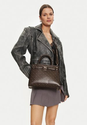 Borsa a tracolla marrone con motivo a GG, texture liscia, doppi manici e tracolla regolabile. Abbinata a una giacca di pelle grigia e a una gonna plissettata.