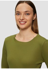 Groene langesleeve shirt met een ronde halslijn, gemaakt van een zachte, gestructureerde stof. Glad afgewerkt en flatterende pasvorm rondom de schouders.