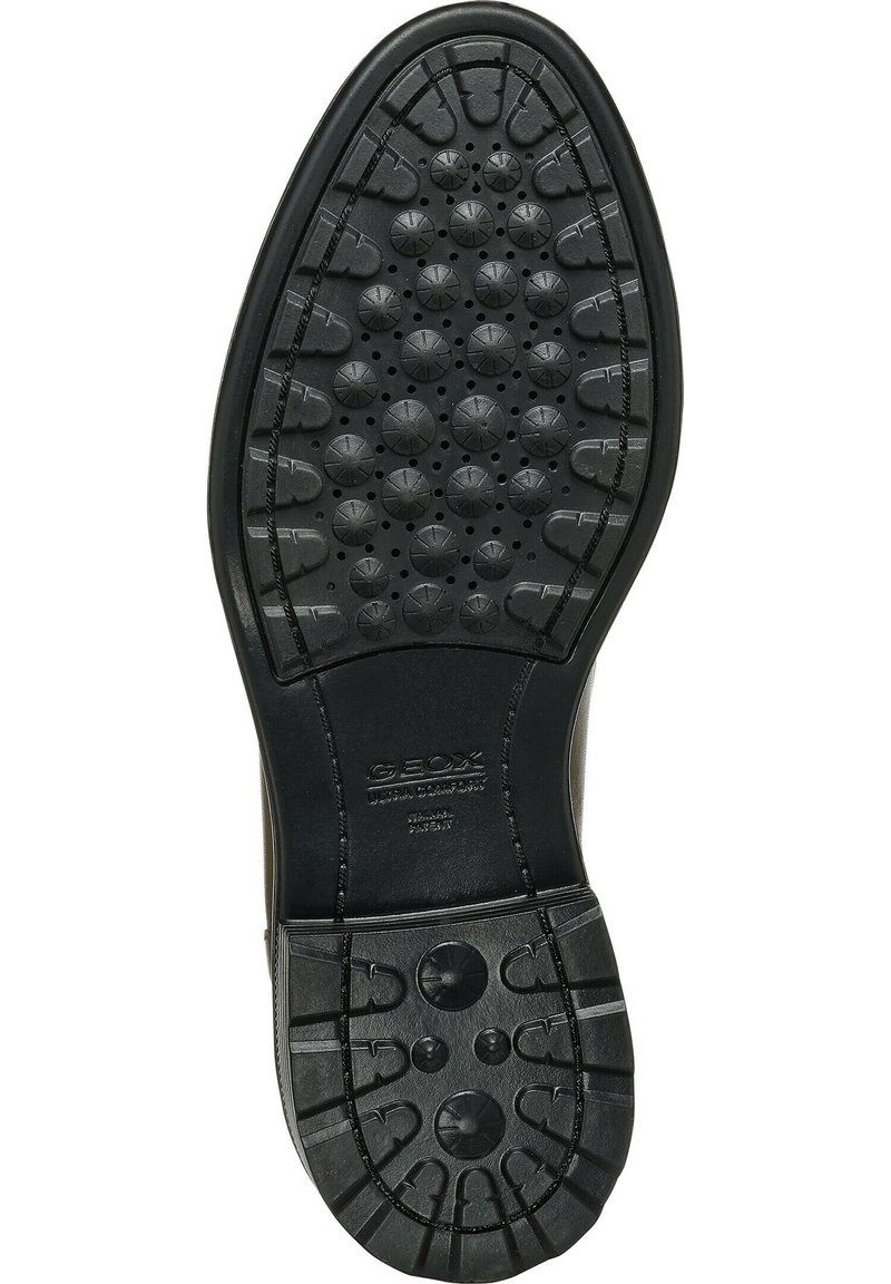 Schwarze Schuhsohle mit runden und hufeisenförmigen Profilmustern, "GEOX"-Markenlabel und Belüftungslöchern für Atmungsaktivität.