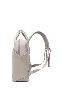 Sac à dos beige clair avec bretelles rembourrées, poche latérale zippée et poignée de transport, affichant un profil latéral sur fond blanc.