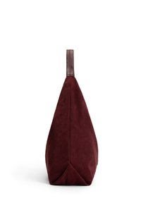 Burgundy suede bag with a sleek, triangular shape and a brown leather handle. Textured surface, minimalistic design, and no visible closure.