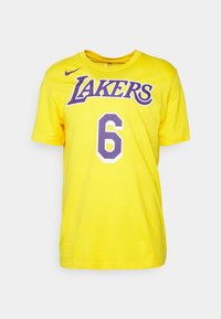 Camiseta amarilla de manga corta con texto en morado "Lakers", número 6 en blanco y morado, y un pequeño swoosh de Nike en morado en el pecho.