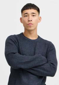 Dark navy ribbed knit sweater with a crew neckline and long sleeves. The texture appears thick and cozy, suitable for cooler weather.