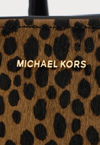 Leopard print handbag featuring a textured brown and black design, with a gold-tone "MICHAEL KORS" logo prominently displayed.