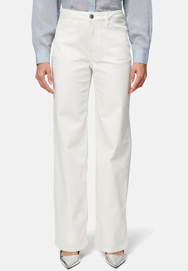 Pantalons larges blancs en denim de coton avec une fermeture éclair et un bouton. Le tissu est lisse avec un léger éclat, adapté à une tenue décontractée.