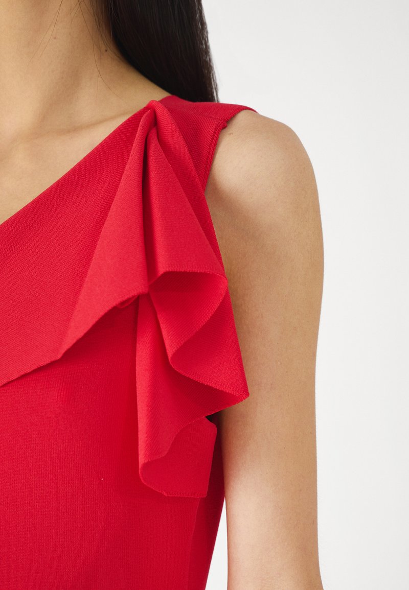 Czerwona sukienka z jednym ramiączkiem, ozdobiona dużą, zwiewną falbaną. Gładki materiał z dopasowanym krojem.