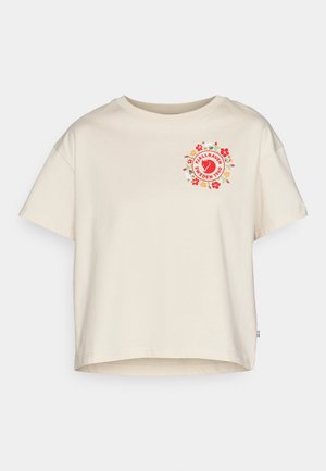 Cream-colored cotton t-shirt with short sleeves, featuring a circular floral logo in red and green on the front, rounded neckline.