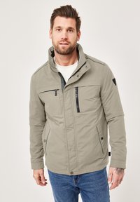 Light grey zip-up jacket with a high collar, two side pockets, a chest pocket, and black accents. Crafted from a smooth, durable fabric.