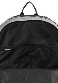 Grau gepolsterte Innenseite eines Rucksacks mit schwarzem Futter, versehen mit einem Etikett. Glatte Textur mit Reißverschluss und einem oberen Tragegriff.