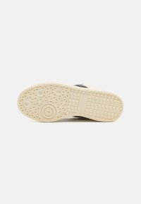 Shoe sole featuring a textured rubber design in off-white with circular and diamond patterns for traction and durability.