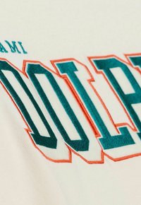 Beige farbener Stoff mit großen, türkisfarbenen und orangefarbenen gestickten Buchstaben, die das Wort "DOLPHINS" in fetter, umrandeter Schrift lesen.