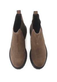 Botines de ante marrón con una textura suave, paneles laterales elásticos y suelas de goma negra. Diseño minimalista y sin herrajes visibles.