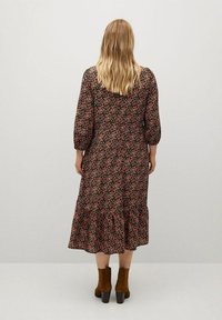 Midi šaty s květinovým potiskem na tmavém pozadí, mají nabírané rukávy, volánkový lem a volný střih. V kombinaci s hnědými kotníkovými botami.