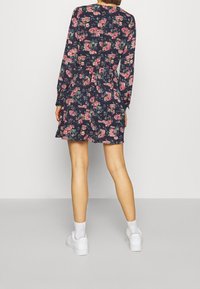 Blumenbedrucktes Kleid in Dunkelblau mit langen Ärmeln, tailliertem Schnitt und ausgestellt Rock. Akzentuiert mit pinken und grünen Blumen.