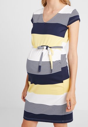 Mujer embarazada con vestido de rayas horizontales de manga corta en azul marino, amarillo y blanco con un cinturón atado en la cintura.