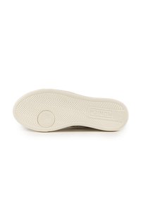 Suola di sneakers in gomma bianca con un motivo a spina di pesce e un logo floreale. Presenta un bordo spesso e testurizzato e un'etichetta del marchio ben visibile.