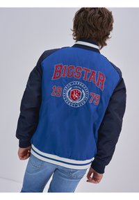 Tumši zils bokseris ar sarkanu izšuvumu "BIGSTAR" un logotipu. Iezīmēts ar ribotiem piedurknēm un jostasvietu ar baltām un tumši zilām svītrām.