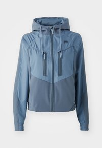 Casaco com capuz azul claro, feito de um tecido suave e elástico. Apresenta bolsos com fecho éclair, painéis contrastantes e uma cintura ajustada.