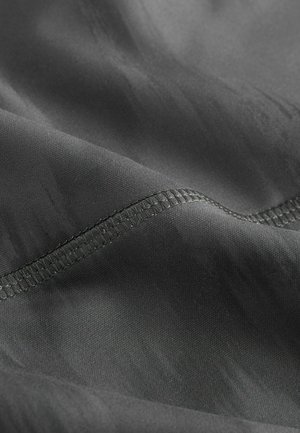 Grau stoff mit glatter oberfläche, der einen subtilen glanz aufweist und eine ordentlich gestickte kante entlang der kurve hat. Keine auffälligen muster sichtbar.