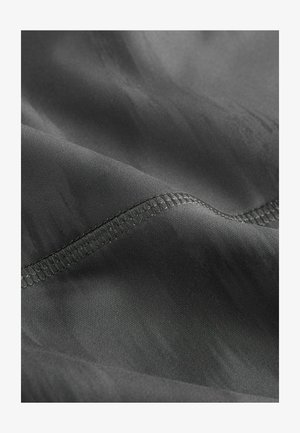 Grijze stof met een gladde textuur, voorzien van een subtiele glans en een net gestikte rand langs de curve. Geen opvallende patronen zichtbaar.