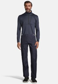 Donkerblauwe lange mouw top met halve rits en een borstzak, gecombineerd met donkerblauwe broek met zijzakken en een verstelbare taille. Getextureerde stof.