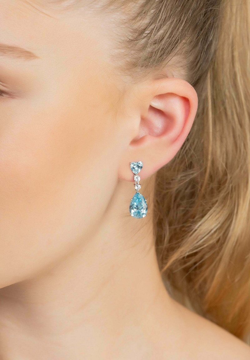 Orecchini in argento sterling con un gemma blu a forma di cuore e una a forma di goccia, arricchiti da accenti trasparenti, con una finitura lucida.