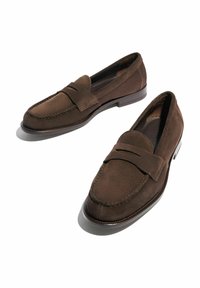 Mocassini in suede marrone con design mocassino, caratterizzati da una punta cucita e una fascia decorativa sul vamp. Suole piatte in gomma.