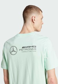Camiseta de algodón verde menta con un logo impreso del equipo AMG Petronas Formula One en la parte trasera, con un clásico escote redondo y mangas cortas.