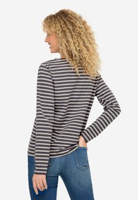 T-shirt à manches longues rayé en marine et crème, avec une coupe décontractée, un col rond et une texture de tissu douce, associé à un jean en denim.