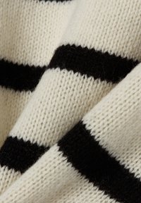 Gebreide trui met crème en zwarte horizontale strepen, met een zachte textuur en een wolmixmateriaal. Close-up van de stofdetails.