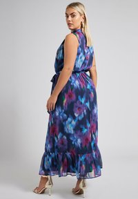 Maxi dress lungo senza maniche con una vivace stampa floreale in viola, blu e rosa. Orlo svasato con dettaglio di volant; tessuto leggero e fluido.