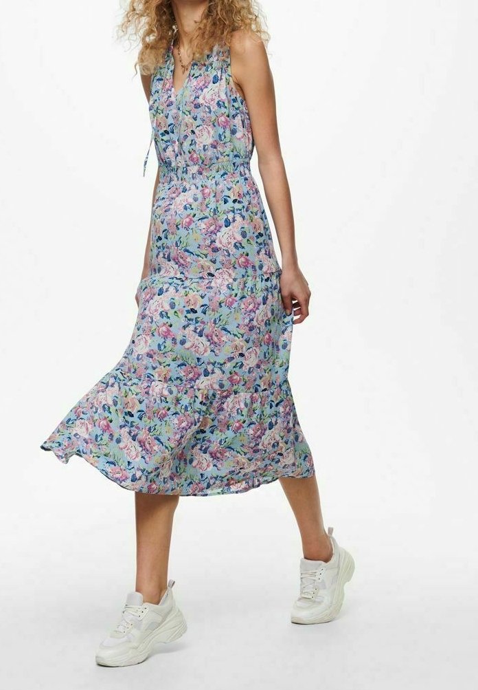 Kukkakuvioinen maksimekko vaaleissa väreissä, jossa on solmittava kaula-aukko, joustava vyötärö ja hulmuava helma. Yhdistettyt tukeviin valkoisiin lenkkareihin.