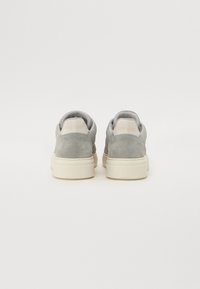 Grå mockaskinn sneakers med rund tå, polstret krage og kremfarget såle. Har subtil merking på hælen. Jevn tekstur over hele skoen.