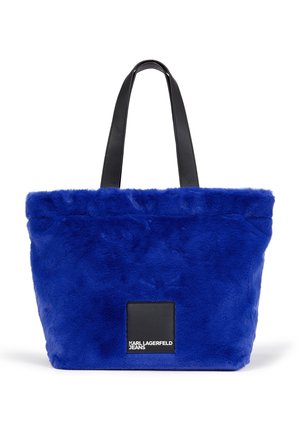 Sac cabas en fausse fourrure bleu avec des anses en cuir noir et une étiquette noire portant l’inscription "Karl Lagerfeld Jeans" au centre avant.