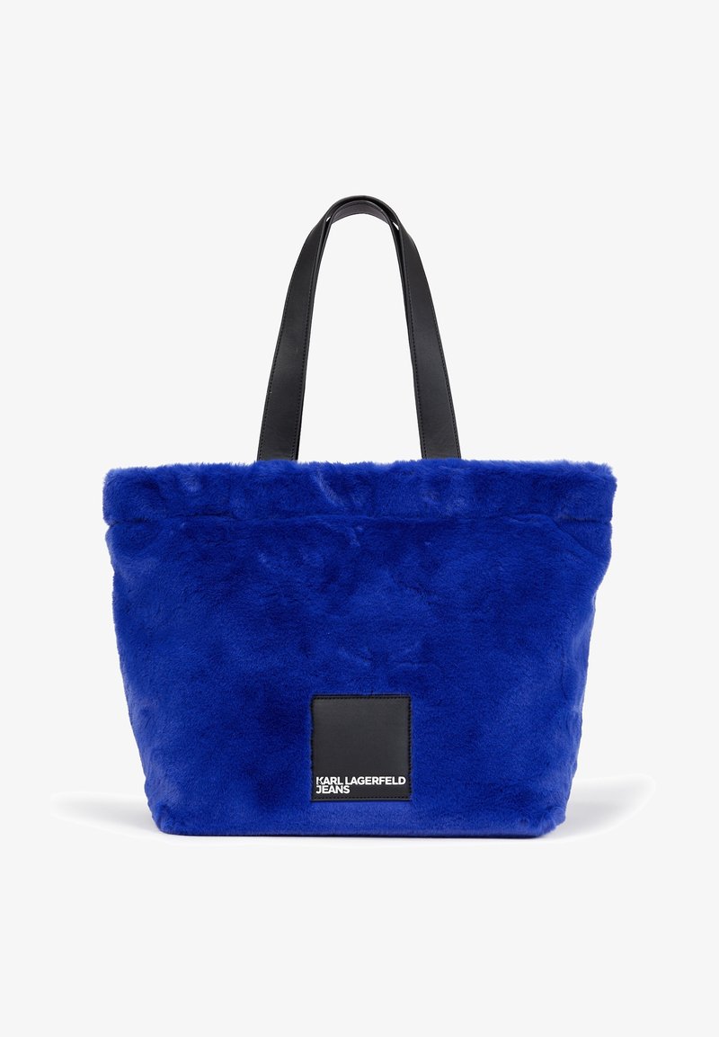 Sac cabas en fausse fourrure bleu avec des anses en cuir noir et une étiquette noire portant l’inscription "Karl Lagerfeld Jeans" au centre avant.