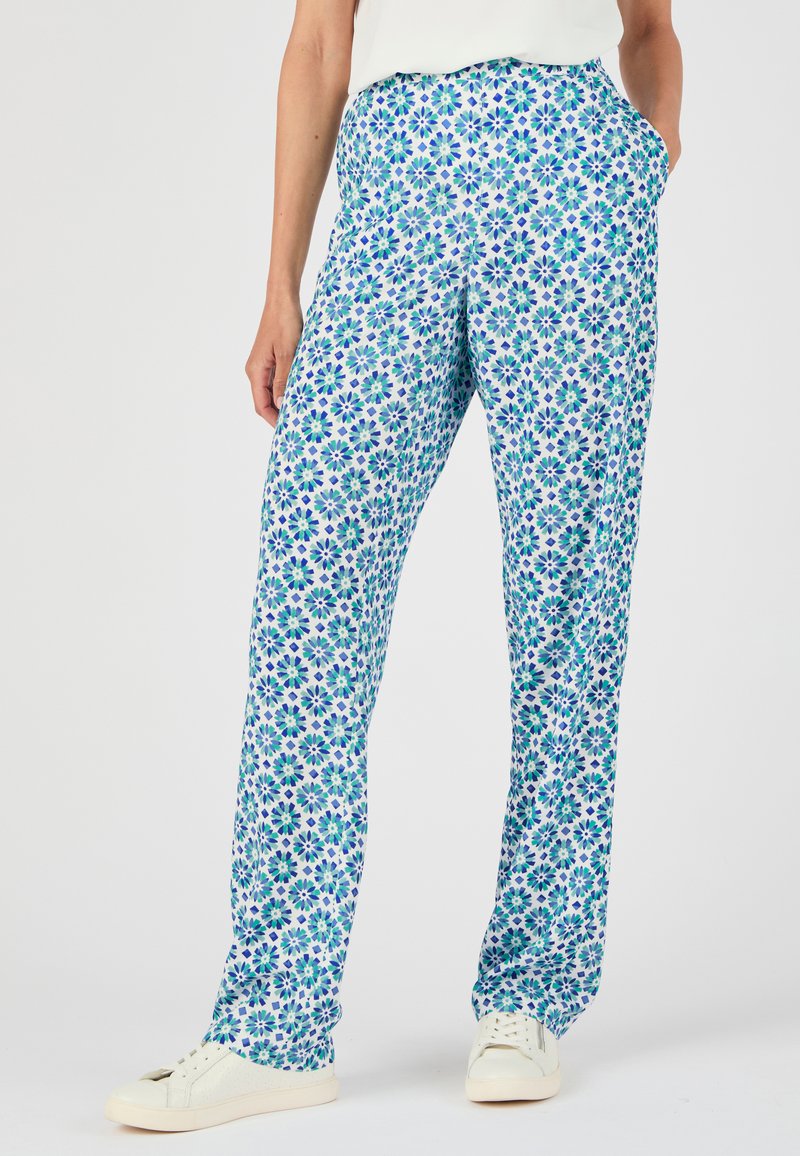Bloemmotief broeken met blauwe en groene bloemen op een witte achtergrond; voorzien van een rechte snit en zijzakken. Gepaard met witte sneakers.