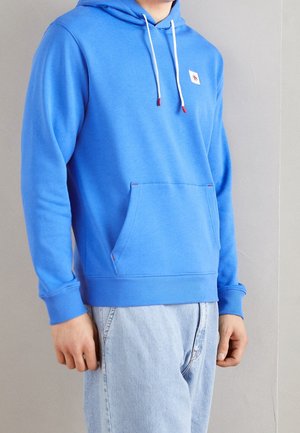 Sudadera con capucha azul en mezcla de algodón, con un bolsillo frontal, cordones blancos y un pequeño parche con el logo. Puños y dobladillo acanalados.