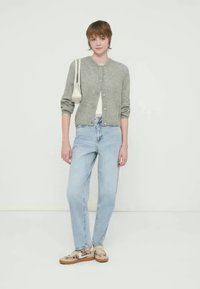 Γκρι ζακέτα, λευκό τοπ, ανοιχτό μπλε τζιν και παπούτσια με σχέδιο. Απλός σχεδιασμός με στρογγυλή λαιμόκοψη, κουμπιά μπροστά και μαλακή υφή.