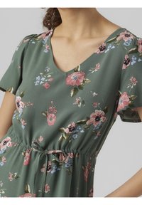 Robe fleurie verte en tissu doux, avec un décolleté en V, des manches courtes et un cordon de serrage à la taille ; décorée de fleurs roses et bleues.