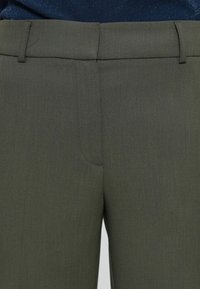 Pantalones de tiro recto de color verde oliva con una textura suave, que presentan un frente plano y presillas para cinturón, sin bolsillos visibles ni cierres a la vista.