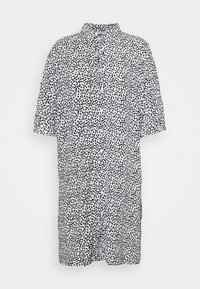 Robe-chemise blanche ample avec motif abstrait à pois noirs, manches courtes, boutonnée devant et col.