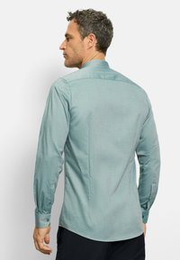Langärmliges Hemd in hellteal mit einem strukturierten Muster, mit klassischem Kragen und geknöpften Manschetten, von hinten gezeigt.