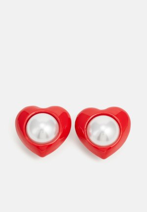 Orecchini a forma di cuore rossi con una finitura lucida e un centro in perla bianca. Texture liscia con un design arrotondato.